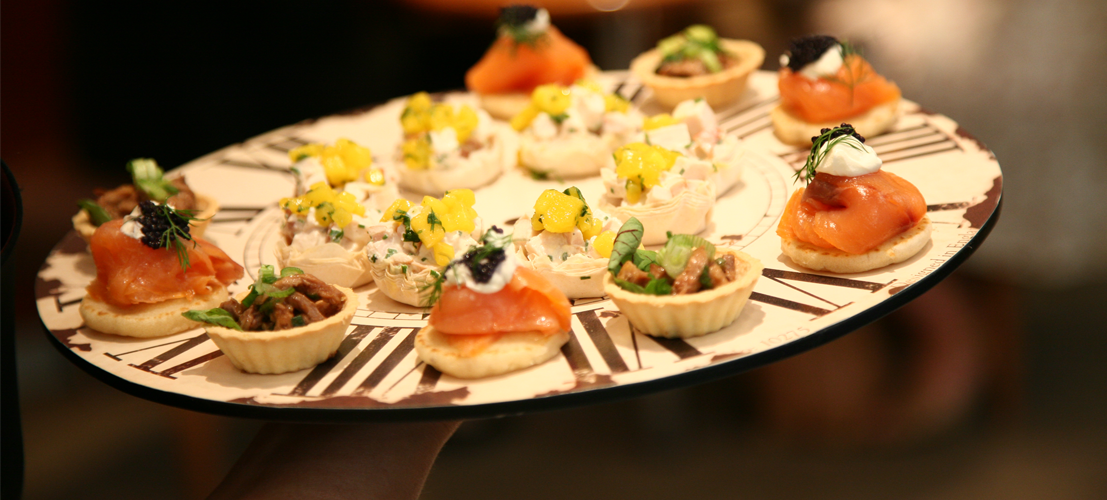 Canapés on a clock-themed platter at a corporate event.