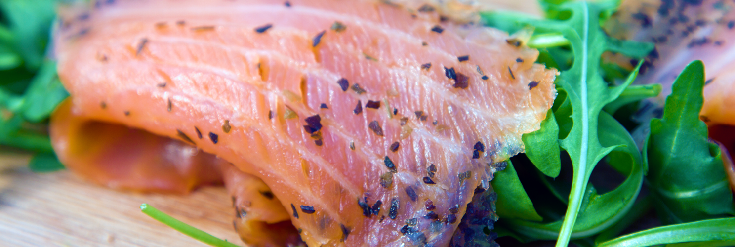 Fresh smoked salmon with rocket on a wooden chopping board.