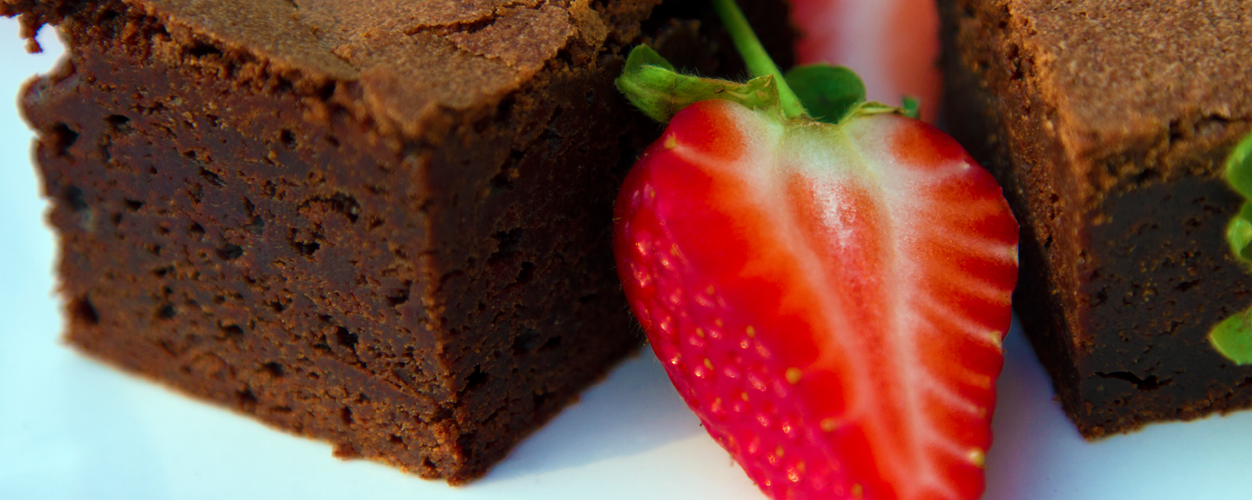 Image of chocolate brownies served with fresh strawberries.